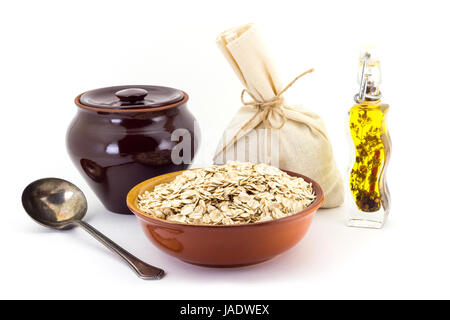 Stillleben mit Oatsmeal Getreide in Keramiktopf pial, Keramik, alte Löffel und Canvas Tasche für Getreide, Öl, Gewürze und Würzmittel, isoliert auf weiß ba Stockfoto