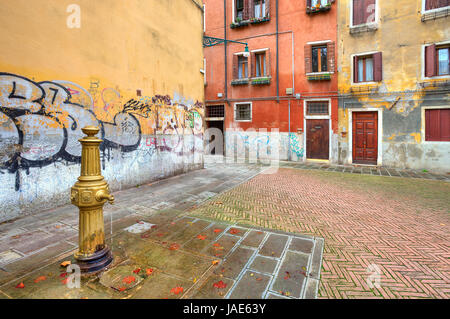 Wasserpumpe auf der kleinen Plaza unter alten typischen venezianischen bunte Häuser und Wände mit Graffiti in Venedig, Italien. Stockfoto