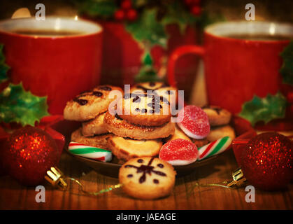 Bild von Weihnachten Dessert, festliche süße Essen Stilleben, zwei Kaffeetassen serviert mit hausgemachten Keksen und verziert mit roten glänzenden Kugeln, lecker Zuckerstange und Lebkuchen, New Year Tabelle festlegen Stockfoto