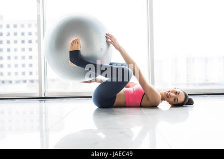 Frau mit Gymnastikball im Fitness-Studio trainieren. Pilates-Frau Übungen in der Turnhalle Fitnessraum mit Fitness-Ball. Stockfoto