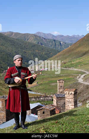 Georgischer Mann in nationalen Kostümen spielt das lokale Musikinstrument als Panduri bekannt, im Dorf Ushguli, in Georgien. Stockfoto