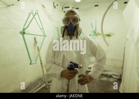 Porträt des Malers halten Farbspritzpistole und mit Gasmaske auf dem Fahrrad workshop Stockfoto