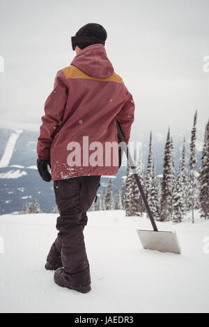 Rückansicht des Menschen halten Schneeschaufel im Skigebiet Stockfoto