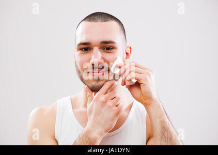 Junger Mann reinigt die Haut auf seinem Gesicht. Stockfoto