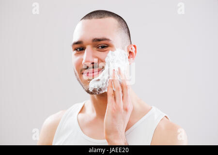 Junger Mann wendet Rasierschaum ins Gesicht. Stockfoto