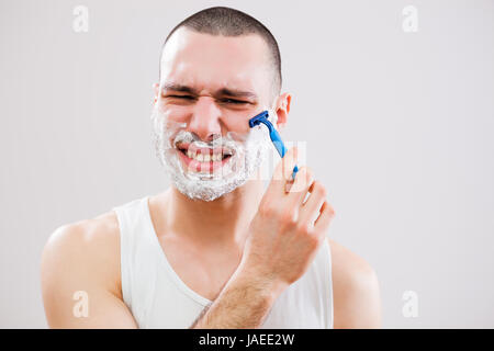 Junger Mann Schnitt sich beim Rasieren Bart. Stockfoto