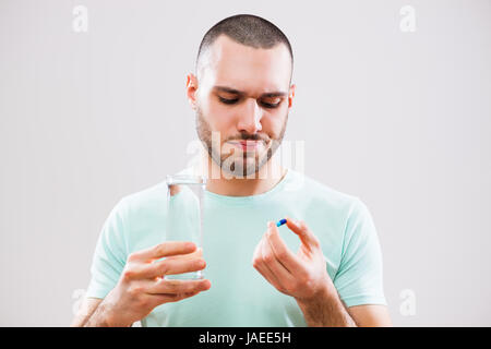 Porträt eines jungen Mannes, die Einnahme eine Pille wegen Krankheit. Stockfoto