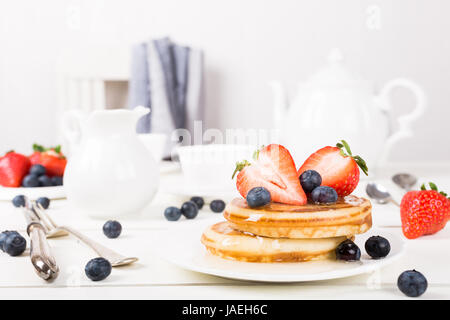 Gesundes Frühstück-Konzept. Hausgemachte Pfannkuchen mit Heidelbeeren, Erdbeeren und Honig. Stockfoto