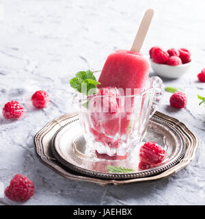 Hausgemachter Himbeer Eis am Stiel im Glas mit Eis, Himbeeren und Minze. Sommer-gesund-Food-Konzept. Stockfoto