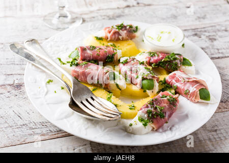 Rollen von Mozzarella, Basilikum und Parmaschinken auf Scheiben von Mango mit Joghurtsauce auf weißen Teller. Gesunde Ernährung-Konzept. Stockfoto