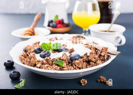 Hausgemachte Schokoladen-Müsli oder Müsli mit Joghurt und frische Heidelbeeren für gesundes Frühstück, selektiven Fokus. Gesunde Ernährung-Hintergrund. Stockfoto