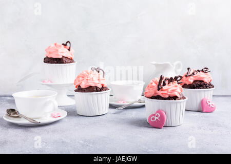 Schöne Schokolade Cupcake, rosa Creme und Herz auf grauem Stein Hintergrund. Valentinstag, Muttertag, Hochzeitskonzept mit Textfreiraum. Stockfoto