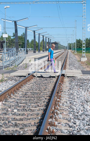 Verfolgt Man in blau zu Fuß über die Eisenbahn Stockfoto