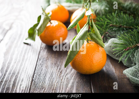 Frische Mandarinen mit Blättern und Reife Mandarinen auf Holztisch Stockfoto