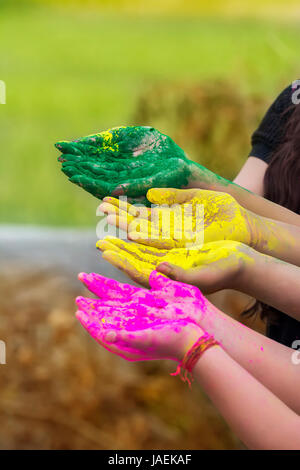 Hände/Palms junger Menschen in rosa, gelb, grün Holi Festival Farben bedeckt isoliert Stockfoto