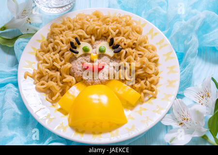 Lustiges Mädchen essen Gesicht mit Schnitzel, Pasta-Nudeln und Gemüse Stockfoto