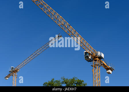 Zwei allgemeine Baukräne auf blauen Himmelshintergrund. Stockfoto