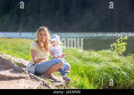 Windiger Tag am Ufer eines Sees. Mutter und Baby Mädchen genießen Sommer Stockfoto