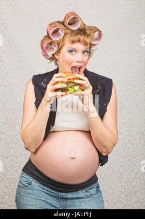 Glücklich weibliche Hinterwäldler in Lockenwickler ein Sandwich zu essen Stockfoto