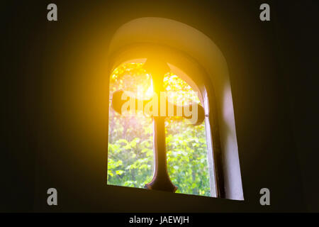 Ein Strahl der Sonne durch das kleine Fenster der Kirche. Stockfoto