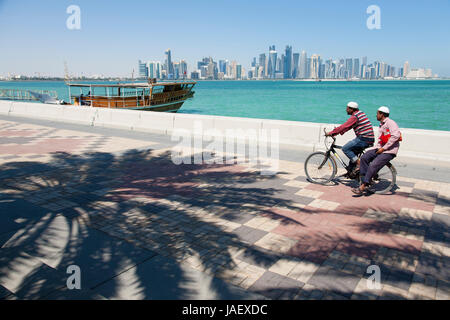 Ein Radfahrer mit PKW-Pedale entlang der Corniche Promenade, Doha, Katar, Blickrichtung West Bay Stockfoto