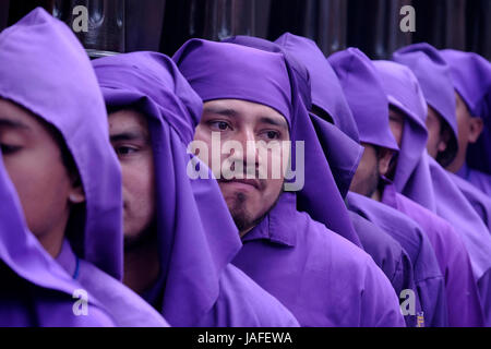 Männer gekleidet in lila Roben tragen die Anda (Float) von Jesus das Kreuz zu tragen, während der Semana Santa oder Heilige Woche fest in San Francisco el Grande Kirche in der Stadt Antigua Guatemala Stockfoto