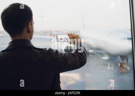 Hübscher Mann stehend neben Glaswand in modernen Flughafenterminal, Foto Bild von Airplane Flugzeug, Reisen in andere Länder. Stockfoto
