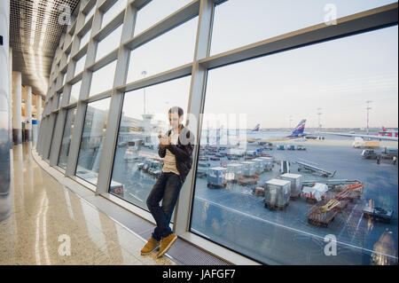 Porträt von ein attraktiver junger Mann zu Fuß und mit Blick auf Handy Stockfoto
