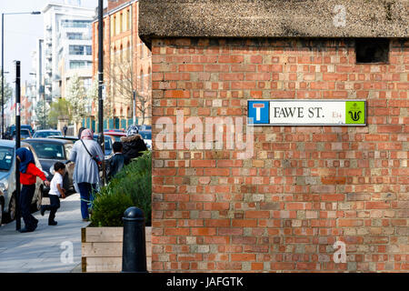 London, UK - 27. März 2017 - Fawe Straßenschild auf eine Mauer mit einer muslimischen Familie im Hintergrund in Pappel, East London Stockfoto