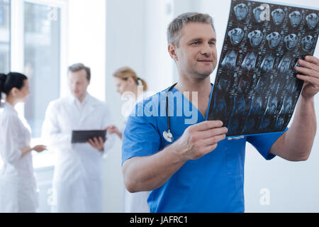 Zu meinen beruflichen Aufgaben durchführen. Erfahrene Reife schön Onkologe an das medizinische Labor arbeiten und mit Blick auf den Ct-Scan während seiner co Stockfoto