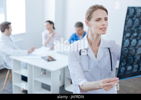 Meine Erfahrungen und Kenntnisse anwenden. Konzentriert, charmante erfahrene Radiologen arbeiten im Labor und untersuchen Ct Scan-Ergebnisse während Kollegen Stockfoto