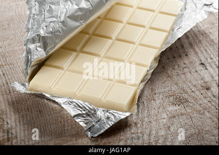 weiße Schokolade bar in Alufolie auf Holztisch Stockfoto