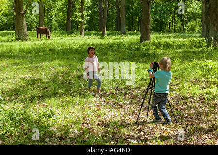 ein wenig junge nimmt Bilder eine Mädchen auf die Natur in einem park Stockfoto