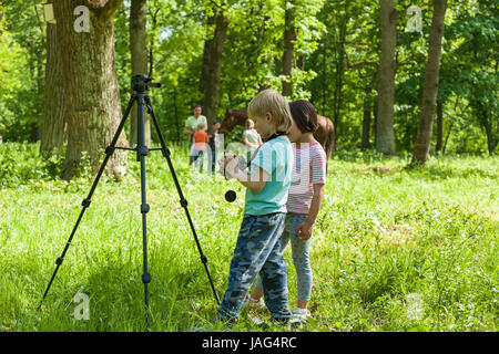 ein wenig junge nimmt Bilder eine Mädchen auf die Natur in einem park Stockfoto