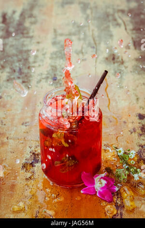 Nahaufnahme von Glas mit erfrischenden Erdbeer-Cocktail mit Limetten, Minze mit Spritzern mit Holz Hintergrund. Stockfoto