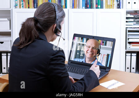 Frau Rechtsanwältin mit Headset vor einem Laptop auf ihrem Schreibtisch, online Beratung eines älteren Client, rechtliche Helpline, kopieren Raum Stockfoto
