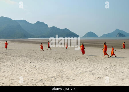 Landschaft Thai Theravada buddhistische Mönche und Novizen in gelb Orange Safran Roben an einem Sandstrand mit Spuren, die Berge und die Natur ringsum Stockfoto