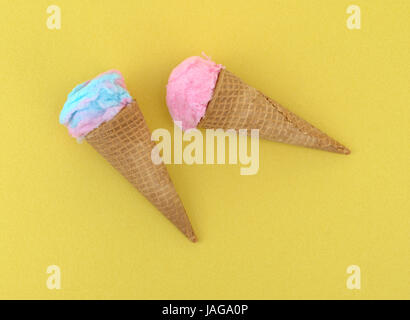 Rosa und blaue Zuckerwatte geformt als Eis in Zuckertüten auf einem gelben Hintergrund. Stockfoto