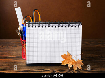 Ausstattung der Schule mit Bleistiften, Notebook und trockenen Herbst Blätter auf Holztisch. Zurück zur Schule oder zum Tag des Lehrers - Konzept. Stockfoto