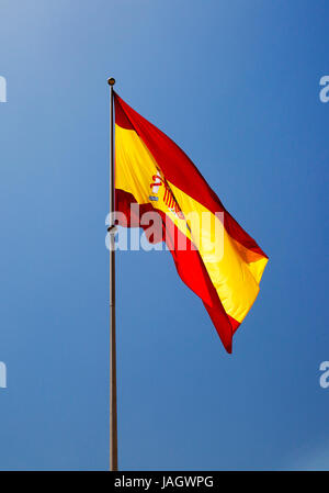 Die spanische Flagge (Bandera de España, umgangssprachlich bekannt als "la Rojigualda") fliegt vor einem tiefblauen Himmel. Stockfoto