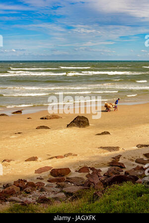 Hawker-Hüte Fuß den leeren Strand ziehen seinen Karren durch den sand Stockfoto