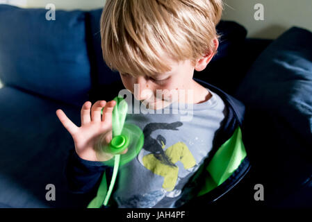 Ein Junge spielt mit einem Fidget Spinner zu Hause das umstrittene Stress Relief Spielzeug gefunden, einige kribbelig oder autistischen Kindern helfen Konzentrat in der Schule Stockfoto