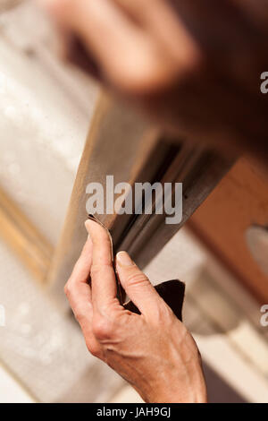 Hände einer Frau mit Sandpapier tun DIY arbeiten auf hölzernen Befestigungen Stockfoto