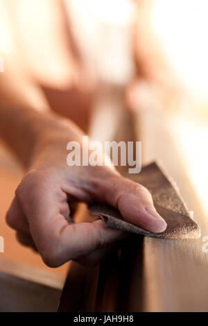 Hände einer Frau mit Sandpapier tun DIY arbeiten auf hölzernen Befestigungen Stockfoto