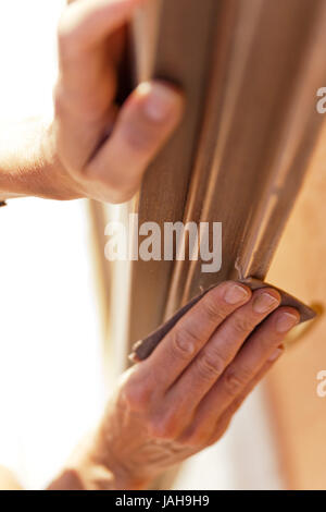 Hände einer Frau mit Sandpapier tun DIY arbeiten auf hölzernen Befestigungen Stockfoto