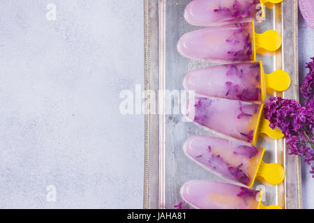 Eis am Stiel mit lila Blumen Stockfoto