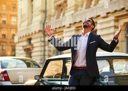 Ein hübscher junger Geschäftsmann stand neben seinem Auto und feiern Stockfoto