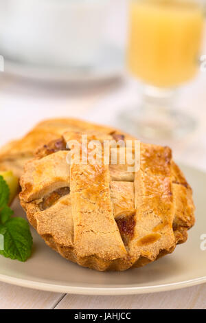 Kleine Runde Apfelkuchen mit Gitter Kruste mit Minze auf einem Teller, heißer Apfel Schlag in den Rücken (selektiven Fokus, Fokus, ein Drittel in den Pie) Stockfoto