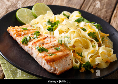 Gegrilltes Lachsfilet mit hausgemachter Fetuccine Nudeln Closeup auf einem Teller. horizontale Stockfoto