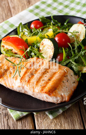 Diätetische Lebensmittel: gegrillter Lachs und Gemüse-Salat mit Rucola Closeup auf einem Teller. vertikale Stockfoto